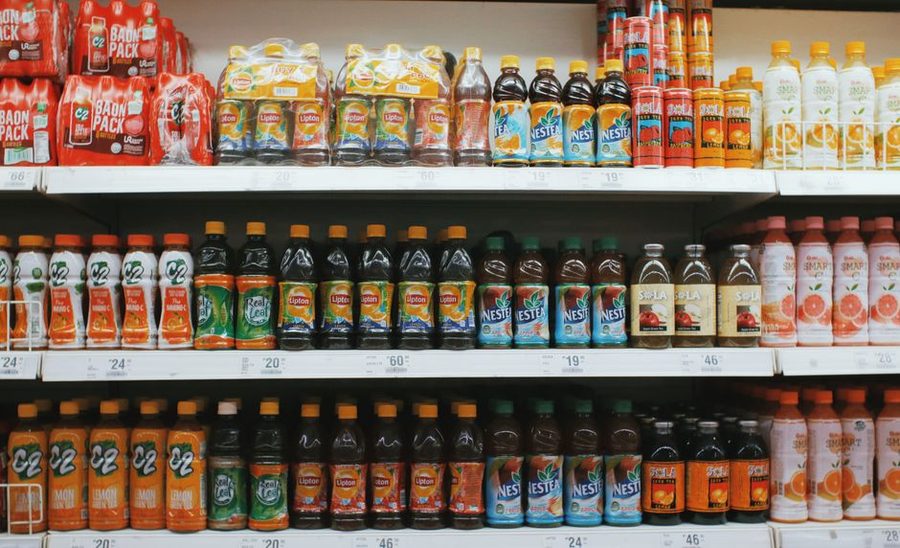 A row of unlabeled glass bottles on a pale shelf in flat daylight